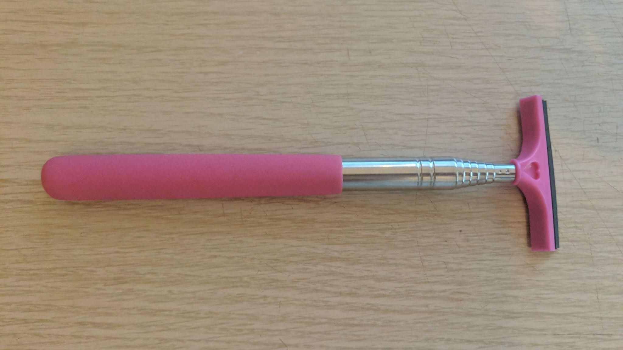 A Pink Stick Em Up Pole on a woodgrain surface