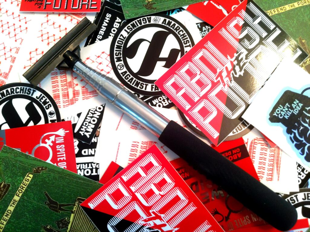 a messy pile of Municipal Adhesives stickers with a Stick Em Up Pole laid atop