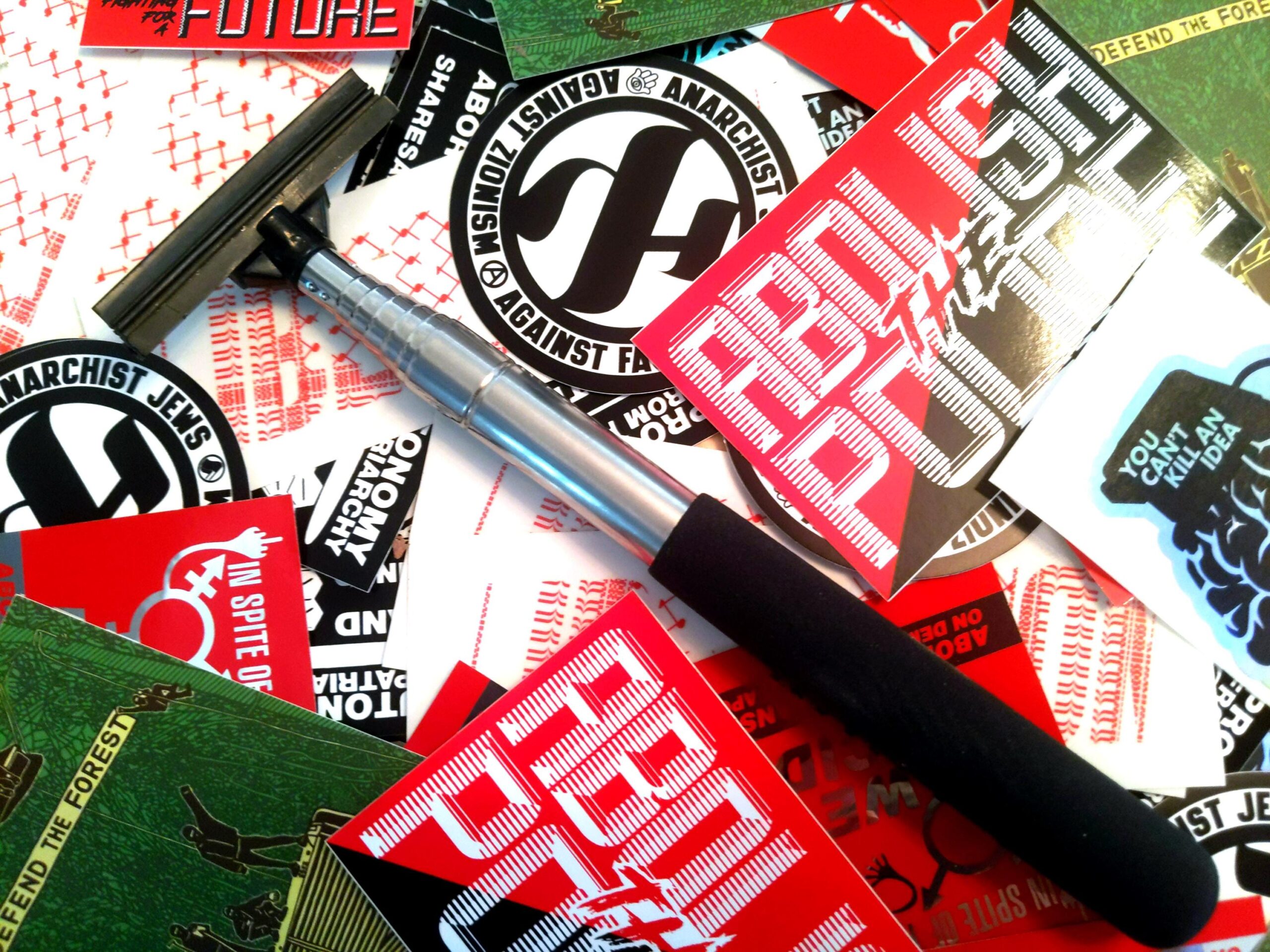 a messy pile of Municipal Adhesives stickers with a Stick Em Up Pole laid atop