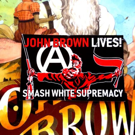 On top of the book jacket for John Brown: His Fight for Freedom, a black sticker in which a three color portrait of John Brown taken from the painting "Tragic Prelude" stands in the center. He holds a Sharps rifle in his right hand and antifascist red and black flags in his left hand. Over his right shoulder looms a large circled A. At the top of the sticker, the words John Brown Lives! in red with the last word white. Across the bottom, the words Smash White Supremacy in white.