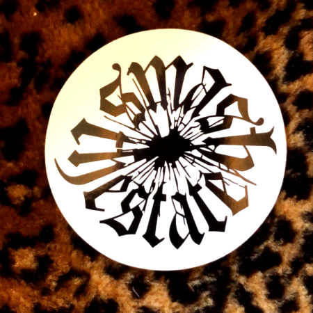 On a backdrop of leopard print faux fur, a black and white sticker with a smashed hole in the center of lowercase blackletter spelling "smash the state"