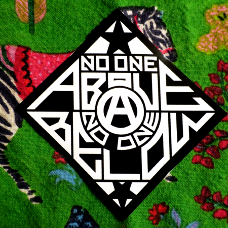 A green cotton print with a zebra on it also bears a sticker on top of it: a black diamond with a circled A in the center, black stars above and below, and the words "No One Above, No One Below" in white text.