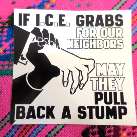 On a pink colorful tapestry, a black and white Municipal Adhesives sticker: a thin white hand in a dark suit with a white exposed cuff that bears a Department of Homeland Security cufflink reaches out but is gripped by a darker hand, stopping it dead. Words reading : "If I.C.E. Grabs for Our Neighbors May They Pull Back a Stump" appear to the right of the two hands.