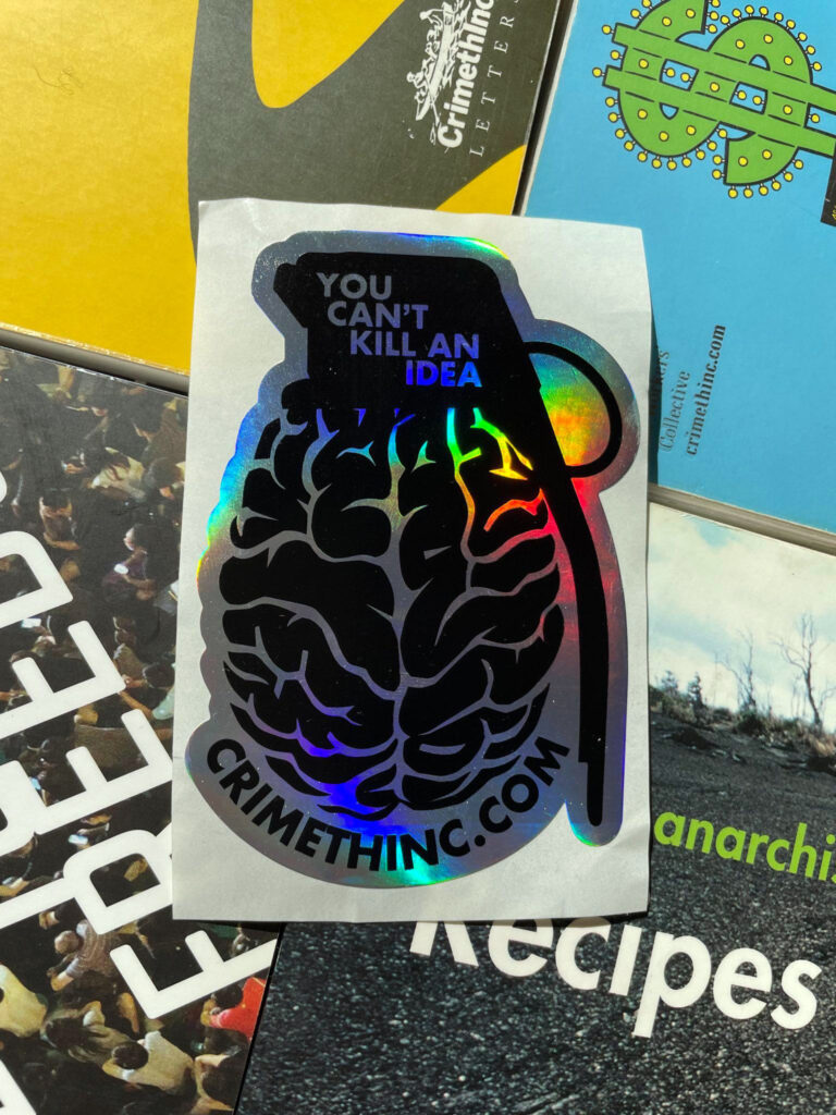 A Municipal Adhesives/CrimethInc. collab sticker: "You Can't Kill An Idea," says the fuze of a grenade with a brain for a charge and body. The url crimethinc.com arcs underneath the brainade. These stickers lay atop a background of CrimethInc. books, including the Unicorn Edition of the Contradictionary, the hardcover edition of Days of War Nights of Love, Work, Off the Map, an ancient edition of Recipes for Disaster, From Democracy to Freedom, No Wall They Can Build, Anarchy in the Age of Dinosaurs.