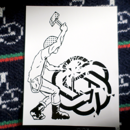 On a navy knit sweater with white bicycles and green and red stripes, a white sticker: An antifascist in boots and braces raises a hammer to smash the logo of ChatGPT and it shatters, propped up by their hand.
